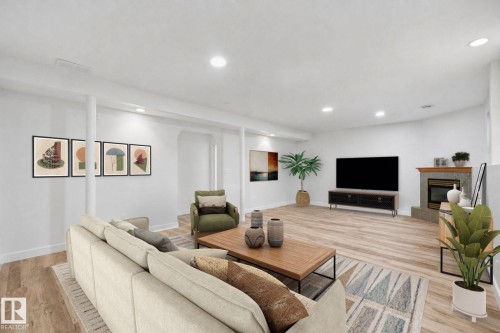Recessed lighting illuminates wood-finish flooring and a corner fireplace with a stone surround - 5132 157 Avenue Nw, Edmonton, AB 
