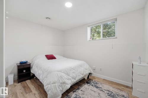 Wood-finish flooring with white baseboards, recessed ceiling lighting, and a white framed window - 5132 157 Avenue Nw, Edmonton, AB 