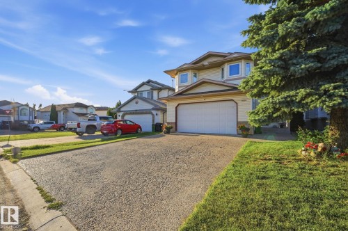 Two-story residence with light-colored siding, an attached garage, and a paved driveway - 5132 157 Avenue Nw, Edmonton, AB 
