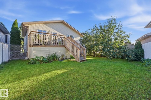 Expansive green lawn with mature trees, a raised wood deck, and a wood staircase - 5132 157 Avenue Nw, Edmonton, AB 