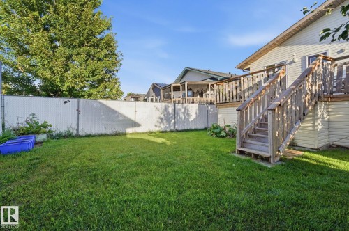 Expansive backyard featuring a manicured lawn, a chain-link fence, and a multi-level wood deck with stairs - 5132 157 Avenue Nw, Edmonton, AB 