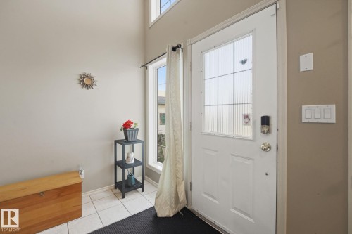 Entryway featuring a white door with frosted glass panels, an electronic smart lock, and white tiled flooring - 5132 157 Avenue Nw, Edmonton, AB 