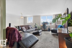 Recessed ceiling lighting and a dropped pendant fixture illuminate the carpeted living space - 