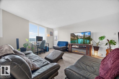 Wall-to-wall carpeting throughout, expansive window, built-in entertainment console with electric fireplace, neutral wall paint, and ceiling-mounted light fixtures - #1102 9916 113 St Nw, Edmonton, AB 