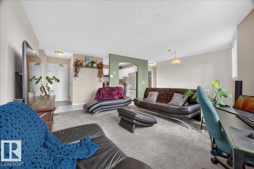 Carpeted living area with light-toned walls, arched entryway, and recessed lighting - #1102 9916 113 St Nw, Edmonton, AB 