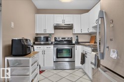 White cabinetry, stainless steel appliances, dark countertops, and tile flooring - 