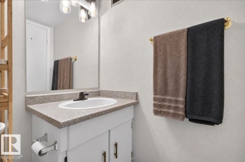 Bathroom vanity with a composite countertop and integrated sink, bronze-finish faucet, and a large wall-mounted mirror - #1102 9916 113 St Nw, Edmonton, AB 