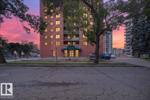Brick exterior high-rise building with multiple windows, framed by mature trees - #1102 9916 113 St Nw, Edmonton, AB 