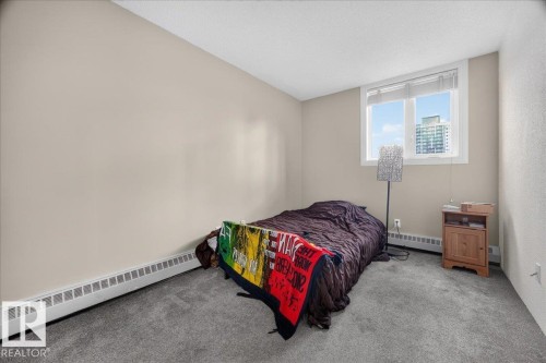 Neutral wall color, carpeted flooring, window with white trim, baseboard heating, and textured ceiling - #1102 9916 113 St Nw, Edmonton, AB 