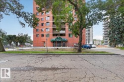 Multi-story brick facade building with multiple balconies, a covered entrance, and mature trees - 