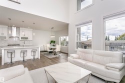 Vaulted ceilings, wood-finish flooring, white cabinetry, a kitchen island with seating, and large windows - 