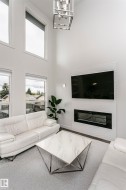 Soaring ceilings, a two-story window array, and a contemporary linear fireplace with a textured surround - 