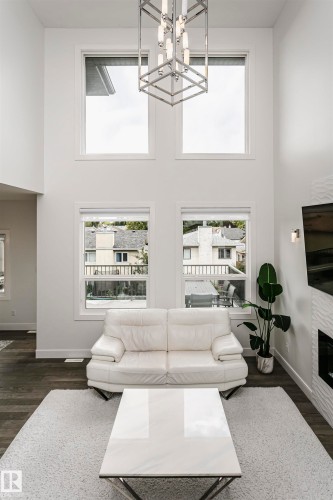 Double-height ceiling with four large windows, contemporary chandelier, and dark wood-finish flooring - 9107 181 Avenue Nw, Edmonton, AB 