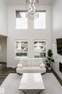 Double-height ceiling with four large windows, contemporary chandelier, and dark wood-finish flooring - 