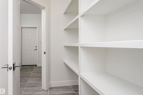 Built-in shelving with white finish, modern interior door with horizontal paneling, and rectangular tile flooring - 9107 181 Avenue Nw, Edmonton, AB 
