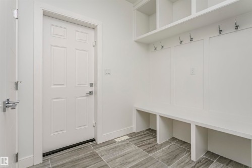 Built-in bench seating with storage, integrated wall hooks, overhead shelving, and large format floor tiling - 9107 181 Avenue Nw, Edmonton, AB 