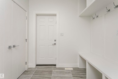 Built-in bench seating with storage, integrated wall hooks, and modern white trim - 9107 181 Avenue Nw, Edmonton, AB 