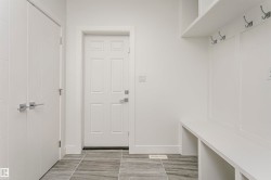 Built-in bench seating with storage, integrated wall hooks, and modern white trim - 