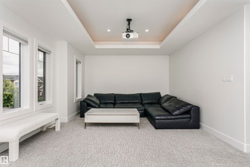 Tray ceiling with recessed lighting and mounted projector, multiple windows, and patterned carpeting - 9107 181 Avenue Nw, Edmonton, AB 