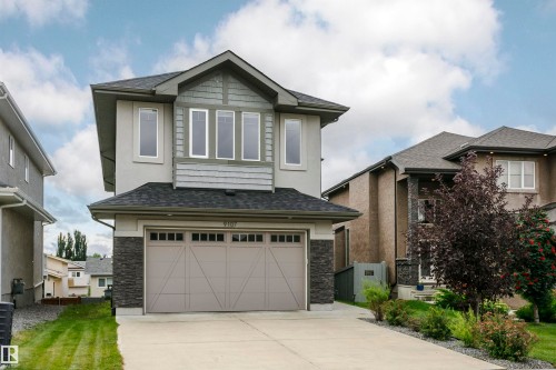 Stucco exterior with stone veneer accents, multi-pane windows, and an integrated garage with a panel door - 9107 181 Avenue Nw, Edmonton, AB 