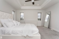 Tray ceiling with recessed lighting and ceiling fan, two windows, textured carpeting, and white walls - 
