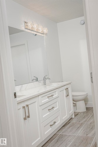 Dual vanity with white shaker-style cabinetry, undermount sinks, and a stone countertop - 9107 181 Avenue Nw, Edmonton, AB 