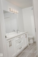 Dual vanity with white shaker-style cabinetry, undermount sinks, and a stone countertop - 