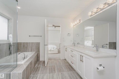 Dual vanity with white cabinetry, polished chrome fixtures, and stone countertops - 9107 181 Avenue Nw, Edmonton, AB 