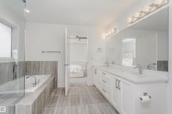 Dual vanity with white cabinetry, polished chrome fixtures, and stone countertops - 