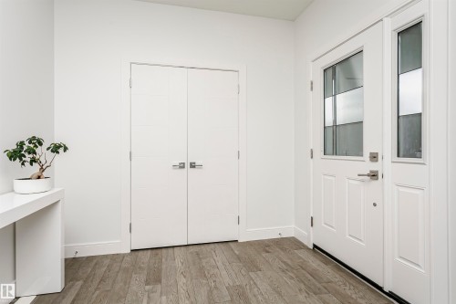 Entryway featuring wood-finish flooring, white walls, and a white paneled door with decorative glass inserts - 9107 181 Avenue Nw, Edmonton, AB 