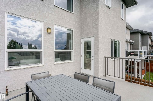 Exterior stucco finish, multiple large windows, glass-paneled door, and a deck with metal railings - 9107 181 Avenue Nw, Edmonton, AB 