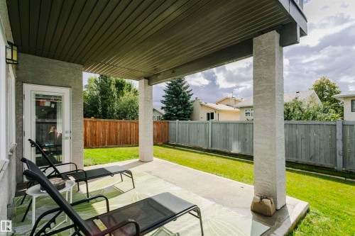 Covered concrete patio with stucco support columns, exterior wall lighting, and a glass-paneled door - 9107 181 Avenue Nw, Edmonton, AB 