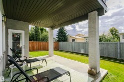 Covered concrete patio with stucco support columns, exterior wall lighting, and a glass-paneled door - 