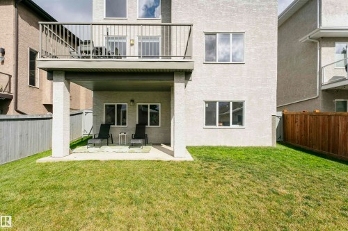 Rear exterior featuring a ground-level patio, upper-level balcony with metal railing, and a fenced yard - 9107 181 Avenue Nw, Edmonton, AB 