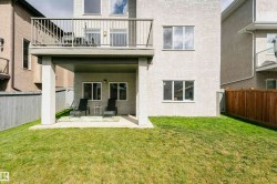 Rear exterior featuring a ground-level patio, upper-level balcony with metal railing, and a fenced yard - 
