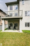 Upper-level balcony with metal railing, lower-level patio, and a manicured grass yard - 