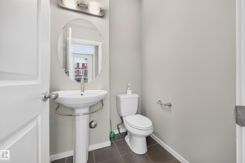 2 piece bath main floor. Pedestal sink with chrome faucet, oval wall-mounted mirror, brushed nickel vanity light fixture. - #72 603 Watt Bv Sw Sw, Edmonton, AB 