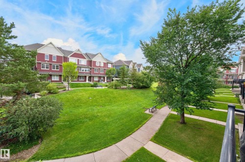 Expansive community green space featuring mature trees, concrete pathways, and lush lawns - #72 603 Watt Bv Sw Sw, Edmonton, AB 