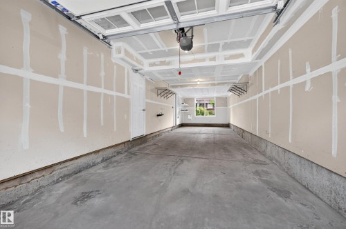 Spacious garage featuring a concrete floor, built-in shelving, a window, and an interior access door - #72 603 Watt Bv Sw Sw, Edmonton, AB 