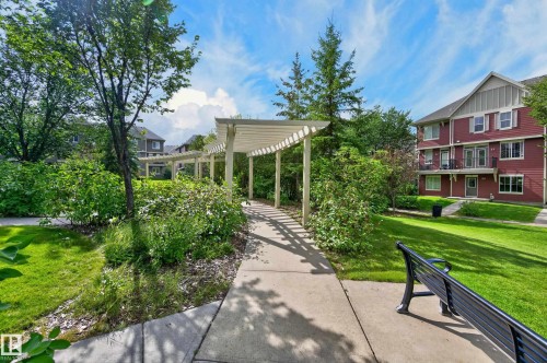 Manicured lawn, mature trees, and a concrete pathway with a white pergola - #72 603 Watt Bv Sw Sw, Edmonton, AB 