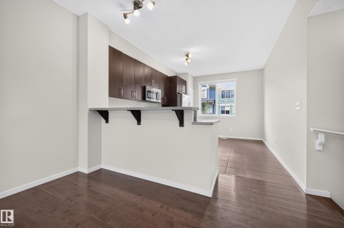 Kitchen with wood-finish cabinetry, stainless steel appliances, and a breakfast bar - #72 603 Watt Bv Sw Sw, Edmonton, AB 