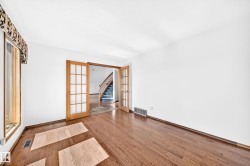 Hardwood flooring, white walls, French doors with glass panels, wood trim around windows, and a staircase with wood banisters - 