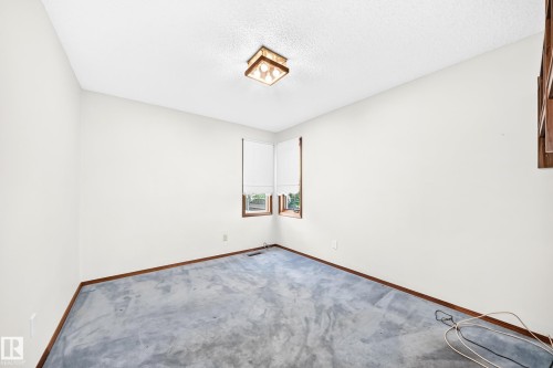 Corner windows with wood-frame trim, overhead ceiling light fixture, and light-colored wall paint - 4208 Ramsay Road Nw, Edmonton, AB 