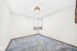 Corner windows with wood-frame trim, overhead ceiling light fixture, and light-colored wall paint - 