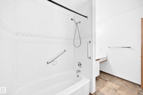 White subway tile shower surround with decorative accent band, complete with a bathtub and shower head - 4208 Ramsay Road Nw, Edmonton, AB 