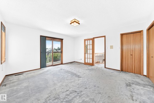 Sliding glass door leading to an exterior deck, interior wood-frame window, full-length double closet doors with wood grain, and a wood-frame French door - 4208 Ramsay Road Nw, Edmonton, AB 