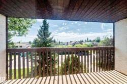 Balcony with wood-paneled ceiling, wood railing, and textured wall finish - 