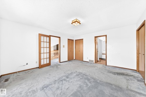 Spacious interior with neutral white walls, light wood-finish doors, and a ceiling-mounted light fixture - 4208 Ramsay Road Nw, Edmonton, AB 