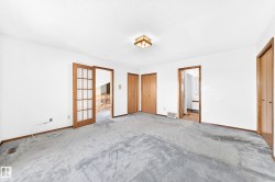 Spacious interior with neutral white walls, light wood-finish doors, and a ceiling-mounted light fixture - 