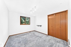 White painted walls, wood-framed window, track lighting fixture, wood-finish bi-fold closet doors, and wood-finish trim - 